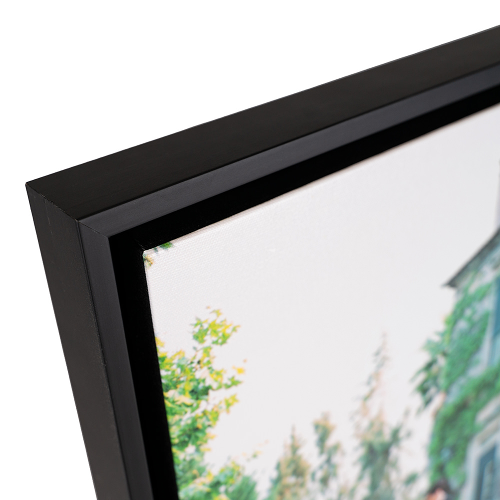 Front corned of a framed canvas with a black frame.